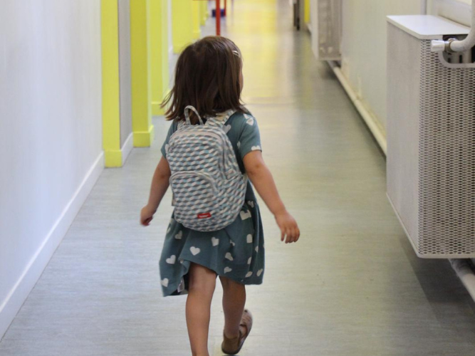 Une enfant qui apporte dans son sac un livre pour sa rentrée en maternelle.